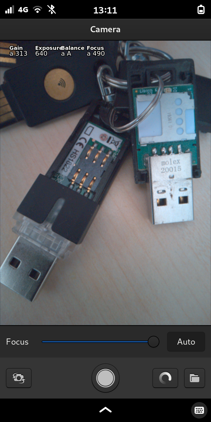 Picture of a modern keychain showing on the left an usb-smartcard-adapter and on the right an opened #LibremKey with the smartcard slot containing its OpenPGP card. In the background there are two yubikeys.